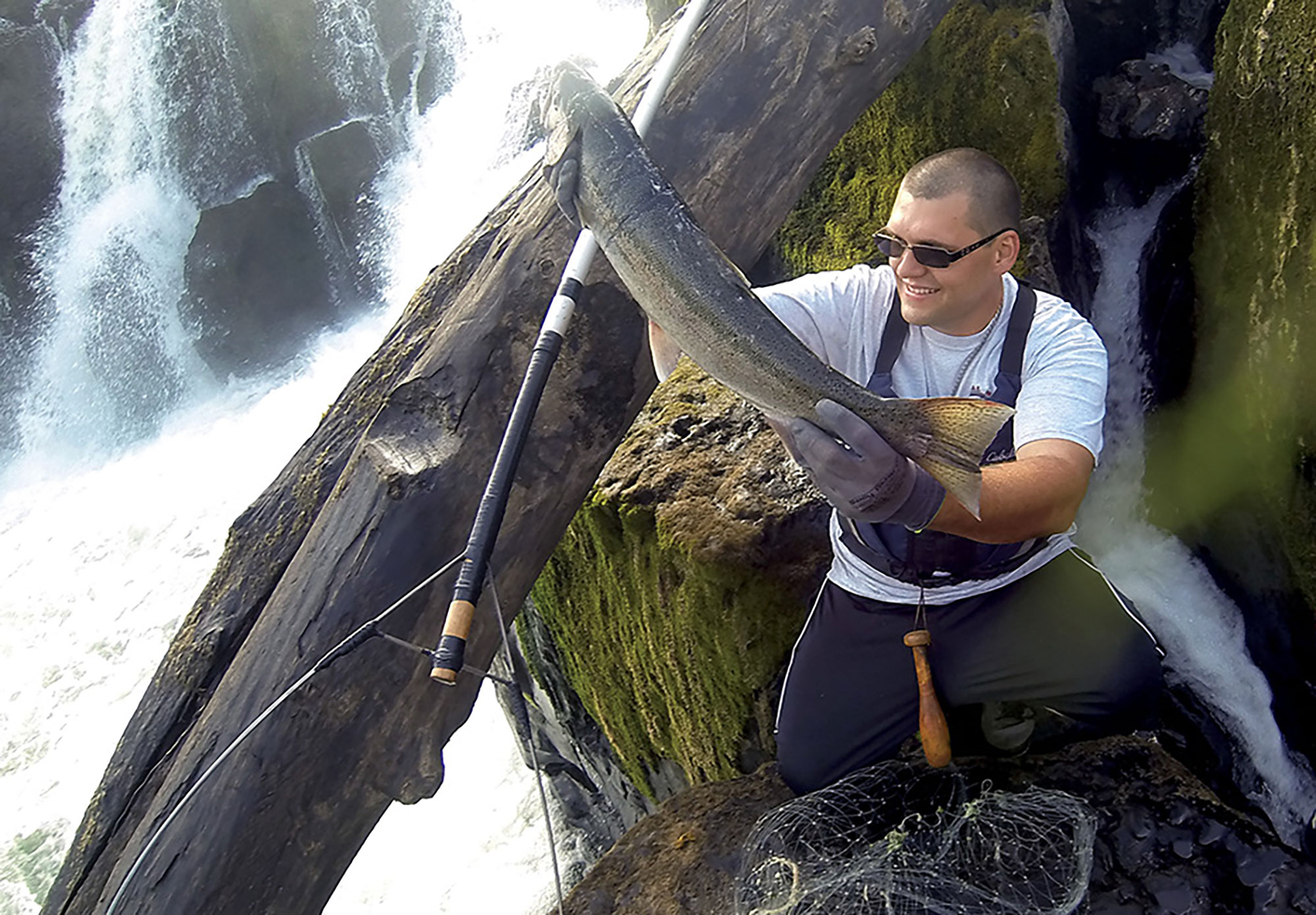 A contemporary member of the Confederated Tribes of Grand Ronde holds up a large salmon freshly caught at Willamette Falls.