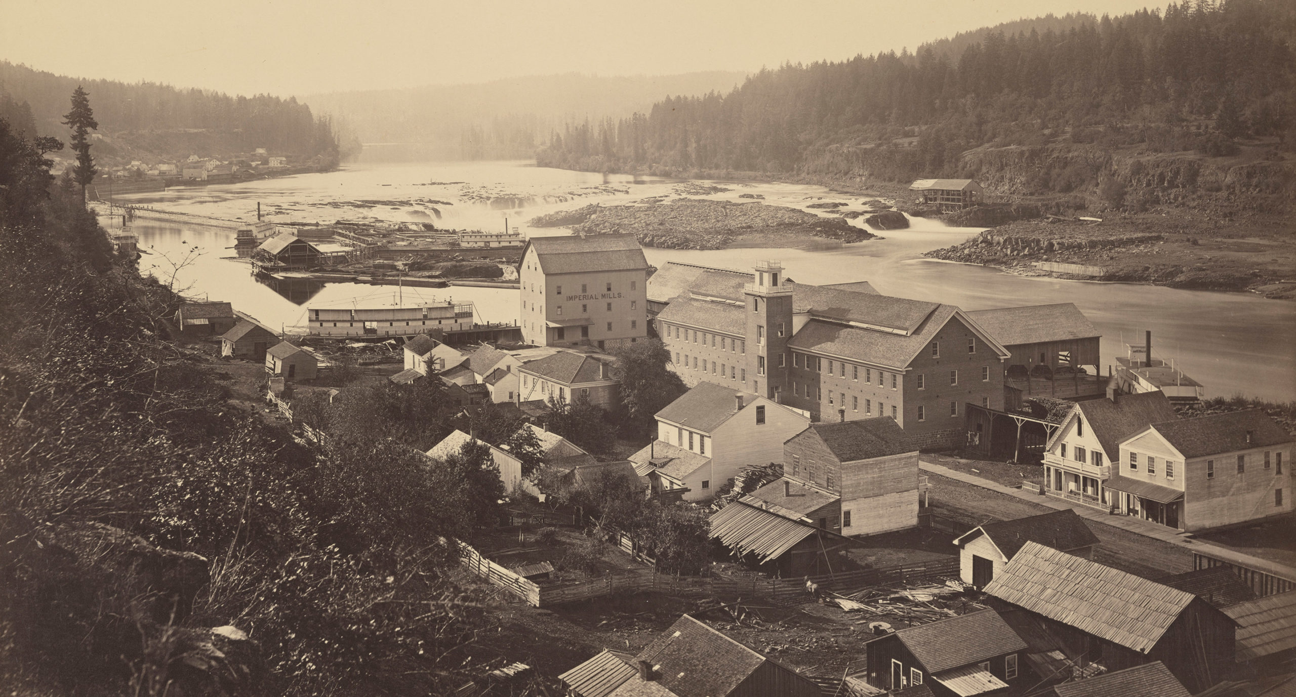 Historical photograph of Oregon City with Willamette Falls in the background.