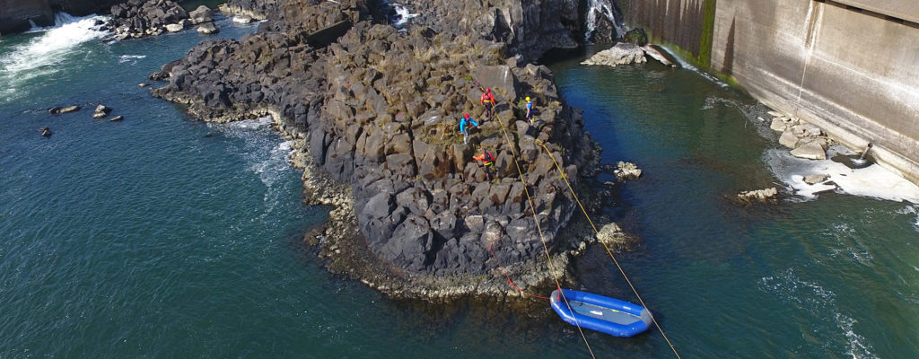 Several people doing work on the rocks near Willamette Falls.