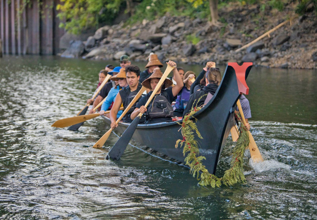 Contemporary members of the Confederated Tribes of Grand Ronde paddle a traditional style canoe near Willamette Falls.