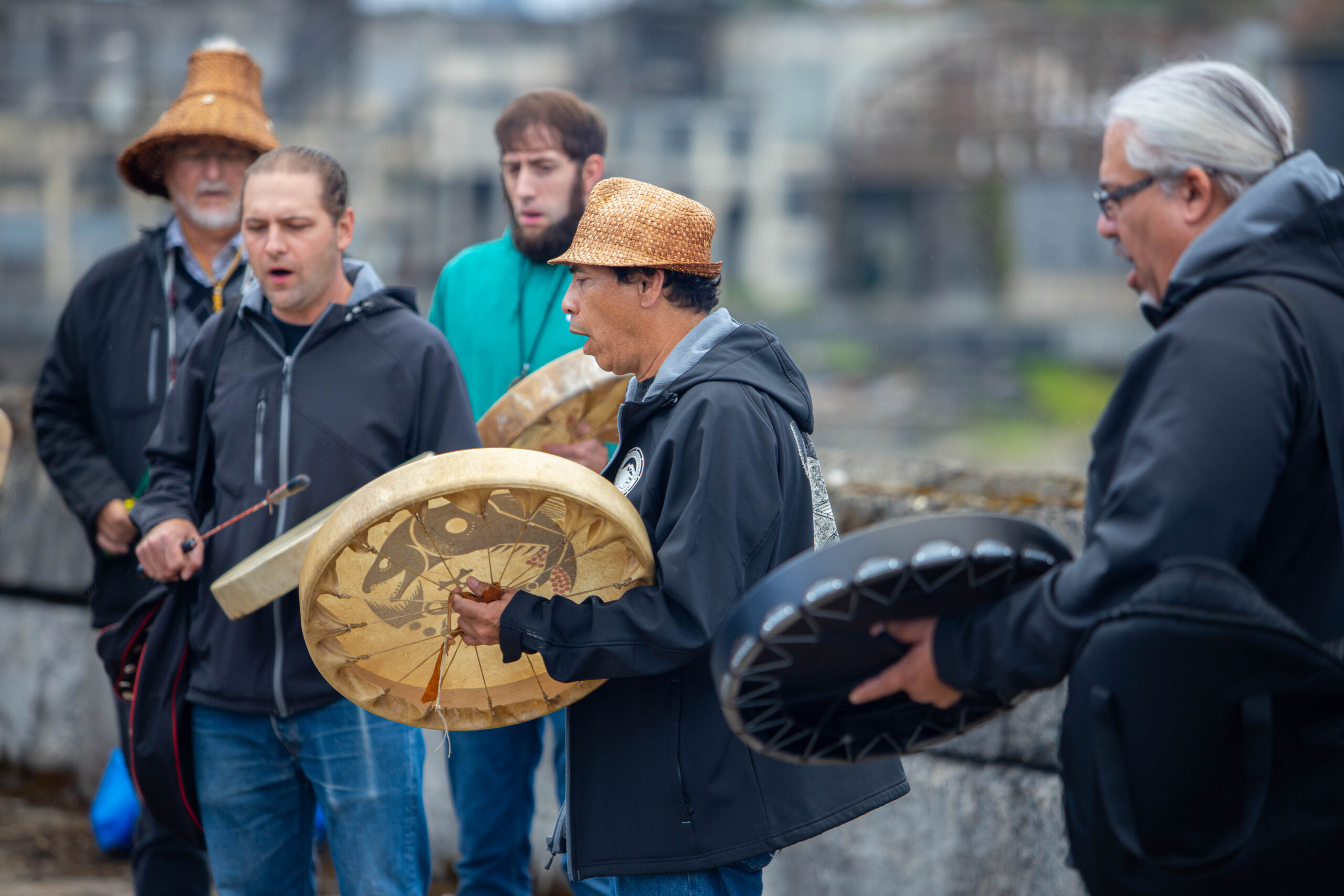Grand Ronde Tribal members playing hand drums and singing.